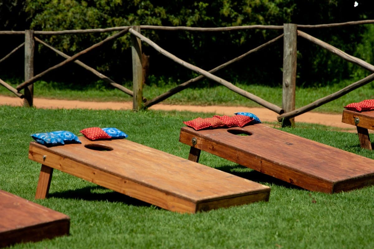 A cornhole board set up on a lawn with bean bags resting on the surface