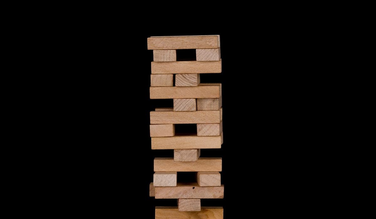 A tall stack of wooden blocks outdoors beside a garden game