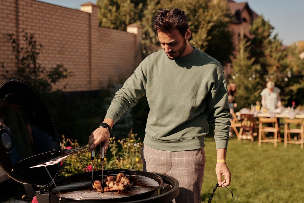 Friends around a grill in a garden at a summer cookout